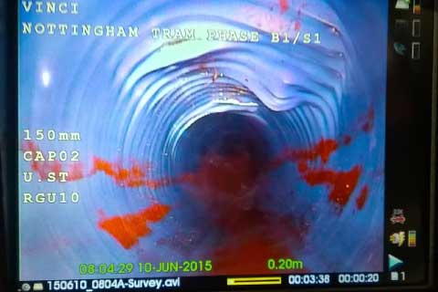 full screen photo of a cctv drain pipe survey showing the internal blue pipe's damage consisting of a sagging, warped, stretched top which apears to be caused by external roots