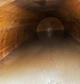 Internal screenshot showing a beige flooded drainage pipe with stagnant water filling approximately 40 percent of the diameter