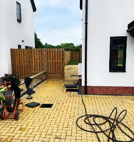 Front left corner of a white Sheffield residential property with CCTV survey equipment set up beside an open drain for survey work