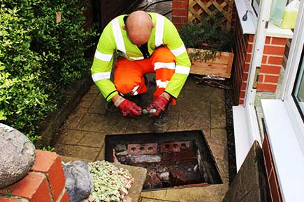 Close-up of an experienced Sheffield drain and sewer jetter preparing to start work on a partially blocked drainage junction in a property�s rear yard.